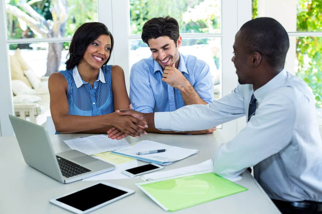 Happy couple shaking hands with a real-estate agent